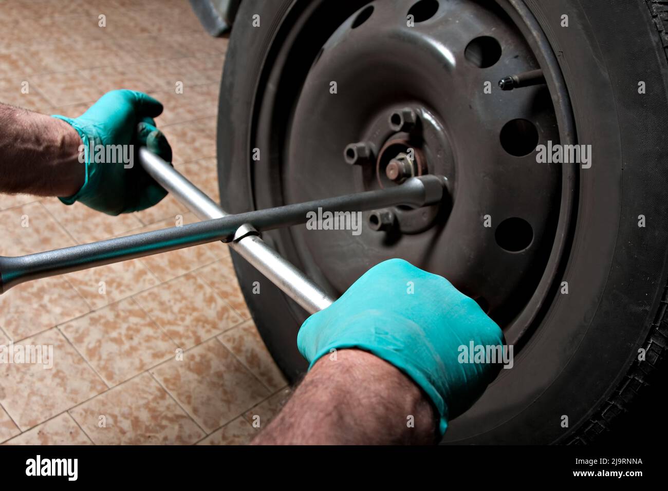 Kfz-Mechaniker Hand mit Kreuzschlüssel zur Demontage der Radmuttern zum Radwechsel. Stockfoto