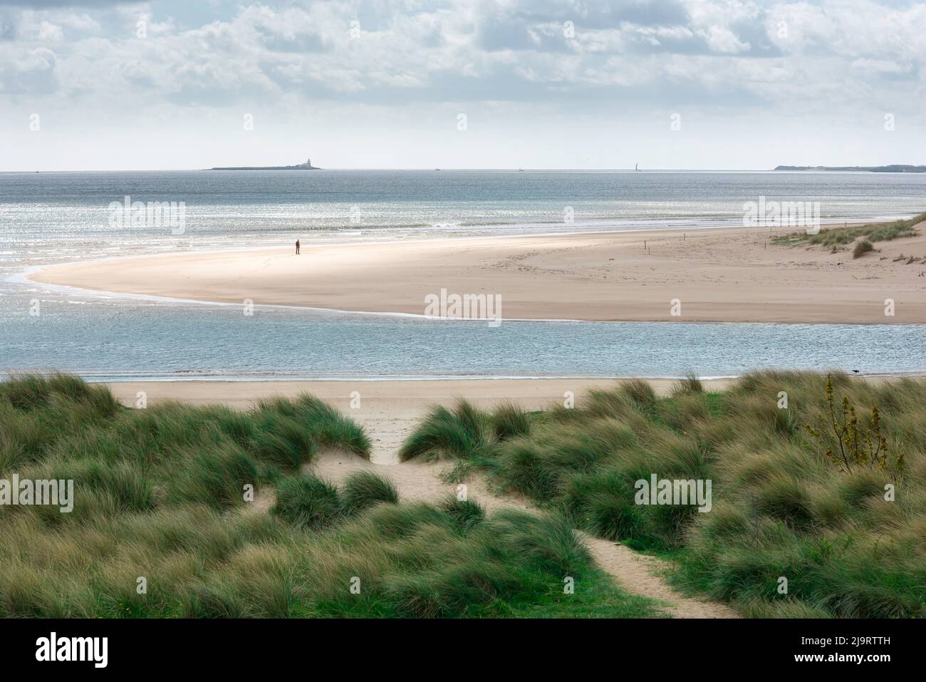 Mann allein, Blick auf eine entfernte männliche Figur, die allein an einem abgelegenen Strand steht. Stockfoto