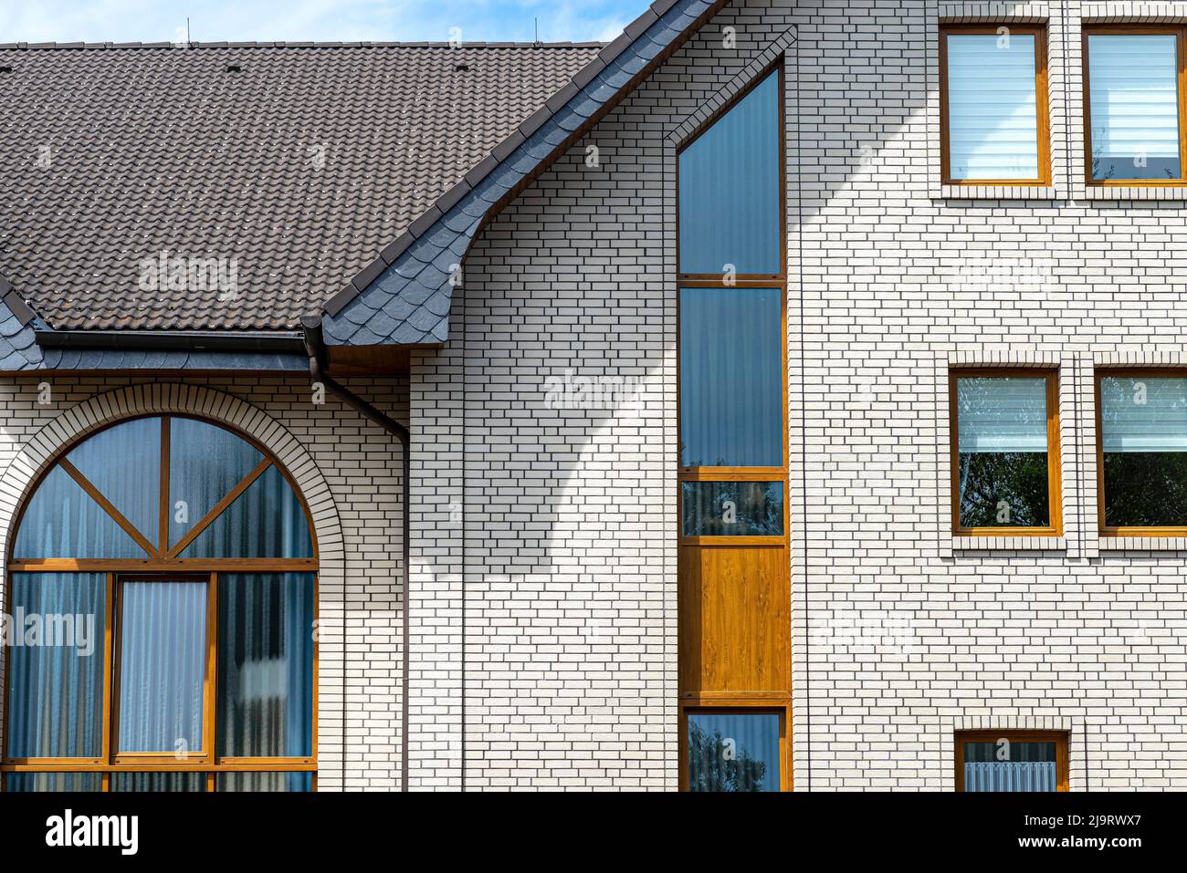 Die Kirche hat eine klassische Fassade aus weißem Backstein und ein konisches Dach, sichtbares halbrundes und rechteckiges Fenster. Stockfoto