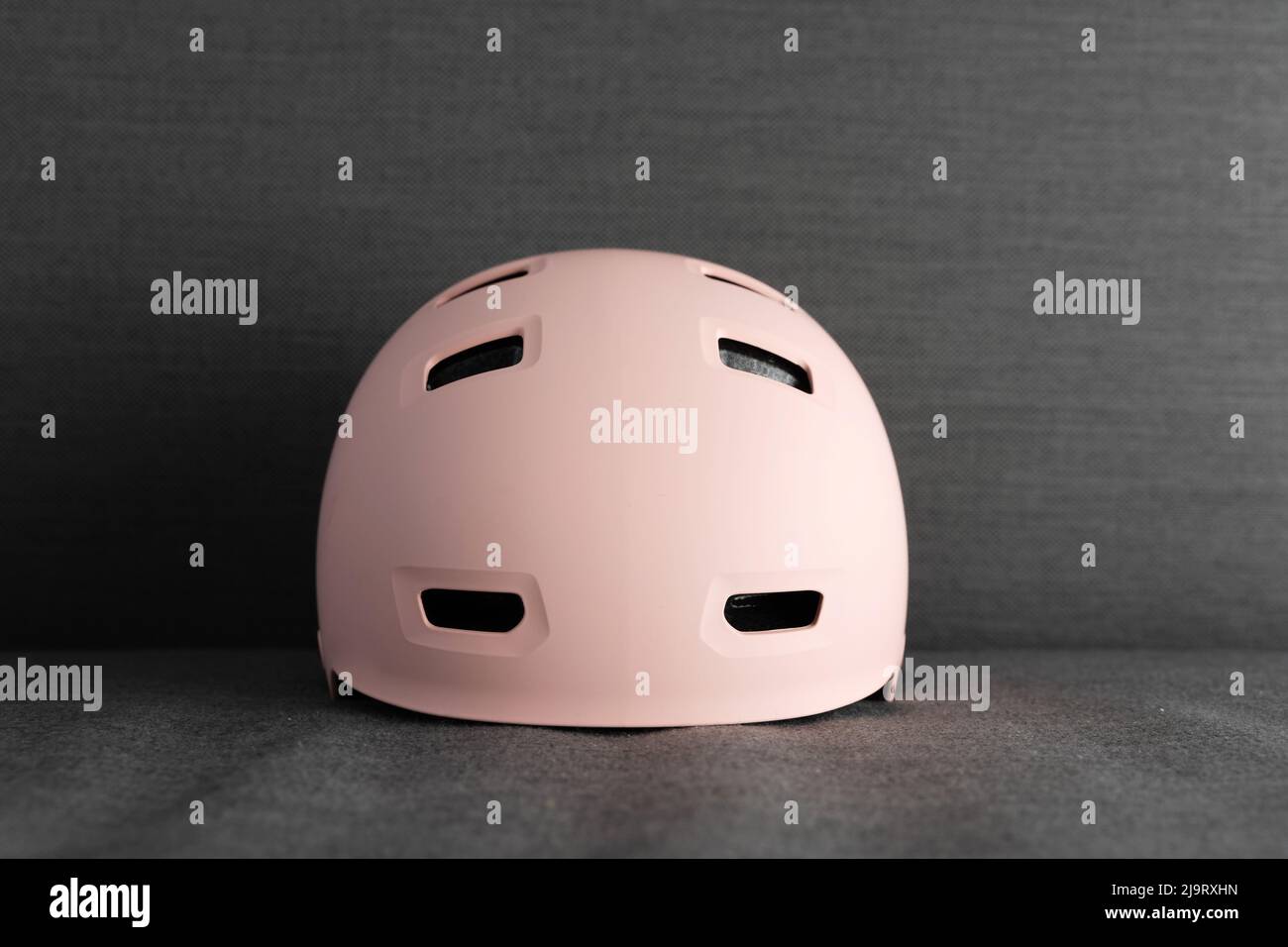 Rosa Helm auf dunkelgrauem Hintergrund. Schutz vor Aktivitäten für Kinder im Freien Stockfoto