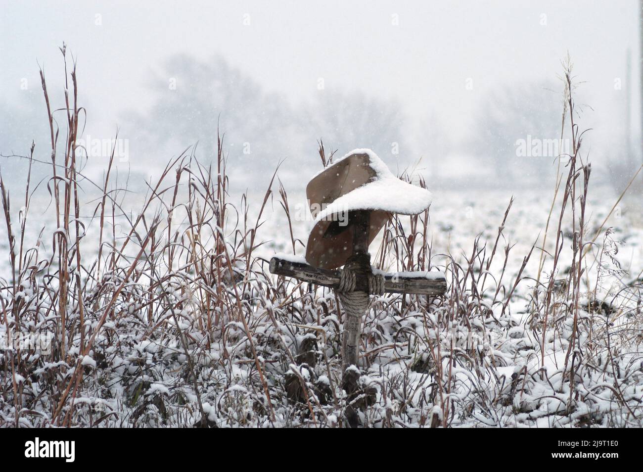 In Erinnerung an einen alten Freund. Kreuz und Hut im Schnee Stockfoto