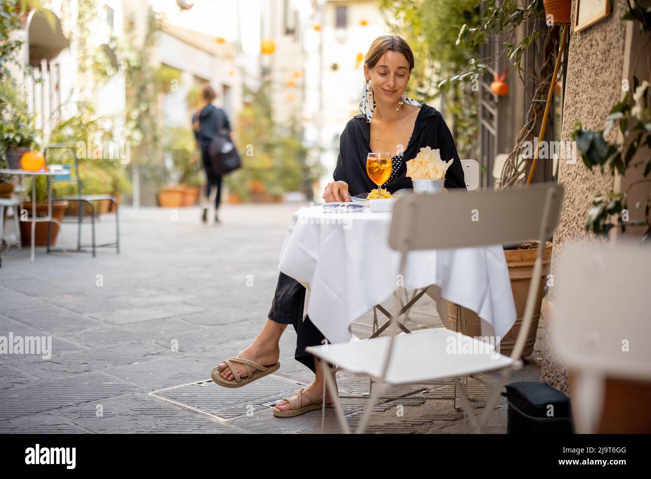 Frau, die im alten italienischen Restaurant zu Mittag mit Pasta und Wein gegessen hat Stockfoto