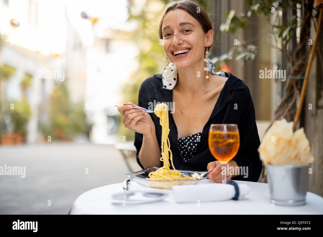 Frau mit Mittagessen mit Pasta und Wein in gemütlichen italienischen Restaurant im Freien. Stockfoto