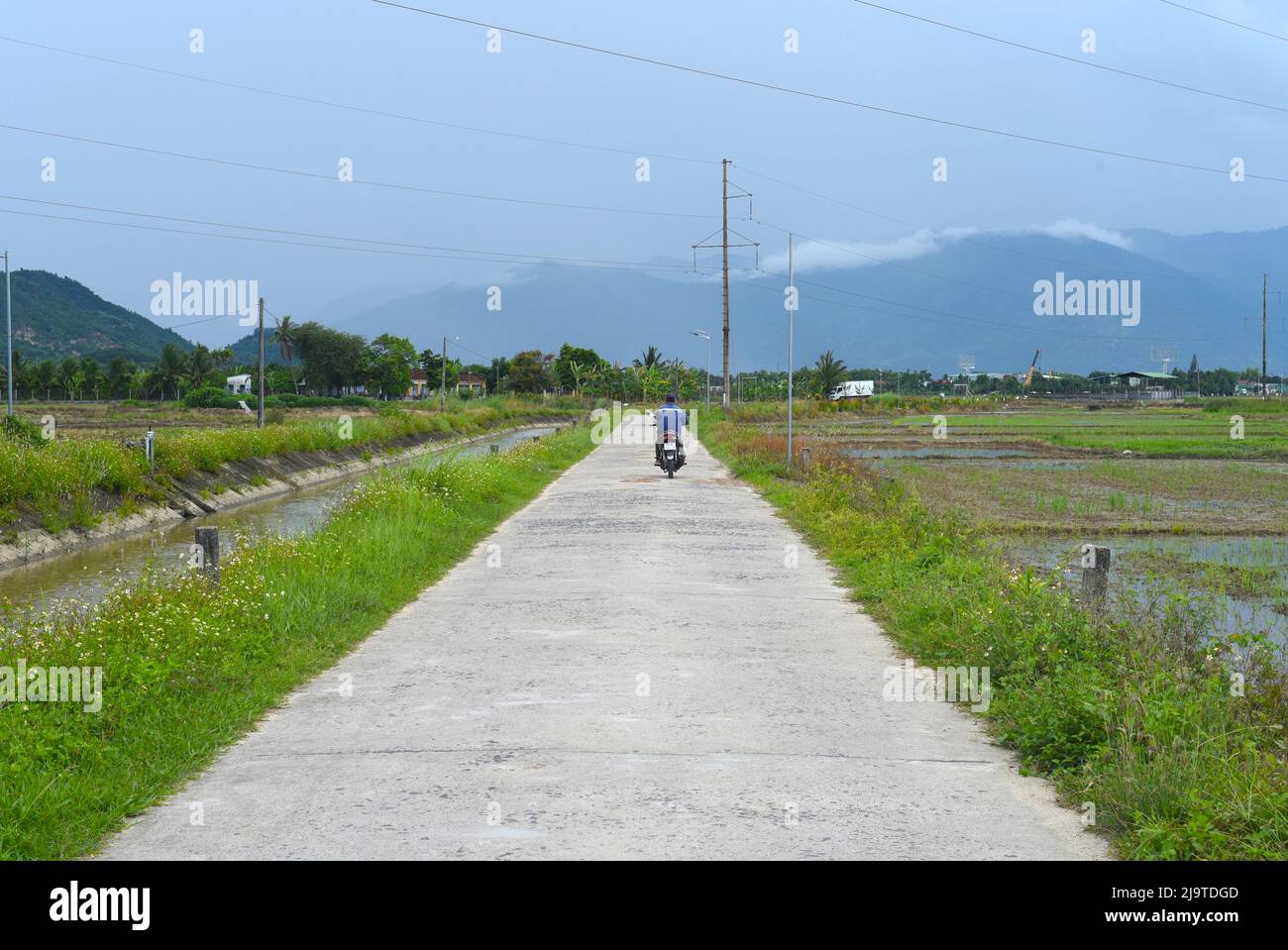 Vietnam - 21. Mai 2022: Landstraße mit Feldern in Vietnam Stockfoto
