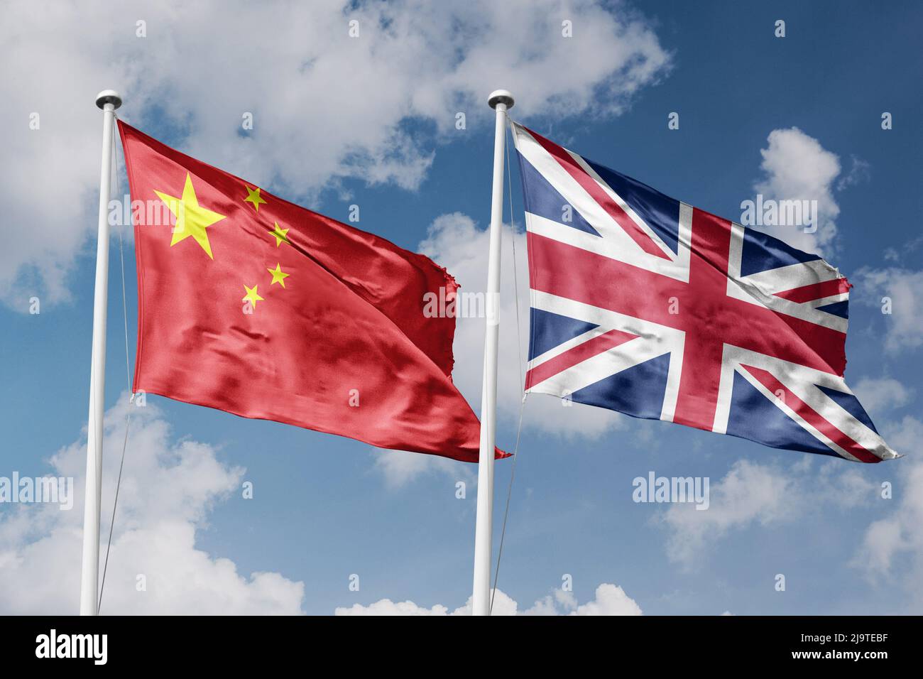 China und Großbritannien zwei Flaggen auf Fahnenmasten und blau bewölktem Himmel Hintergrund Stockfoto