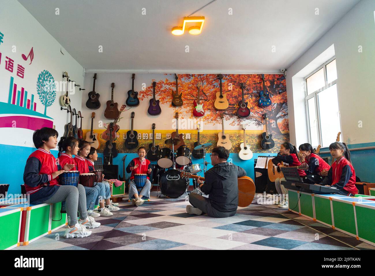 (220525) -- HARBIN, 25. Mai 2022 (Xinhua) -- Lehrer Zhang Yu und Kinder in der Musikklasse üben für Bandaufführungan der zentralen Grundschule der Stadt Renmin in der Stadt Anda, nordöstlich der Provinz Heilongjiang, 24. Mai 2022. Die Musikklasse der Grundschule wurde im April 2019 gegründet. Die Lehrer der Klasse passen die Texte der populären Lieder an, damit die Kinder singen können, und unterrichten sie ihnen dann während der Mittagspause oder der Clubaktivität. Die Kinder-Chorus-Videos wurden auf kurzen Videoplattform veröffentlicht, die von vielen Netzzenen beliebt war und über 1 Millionen verdient hat Stockfoto