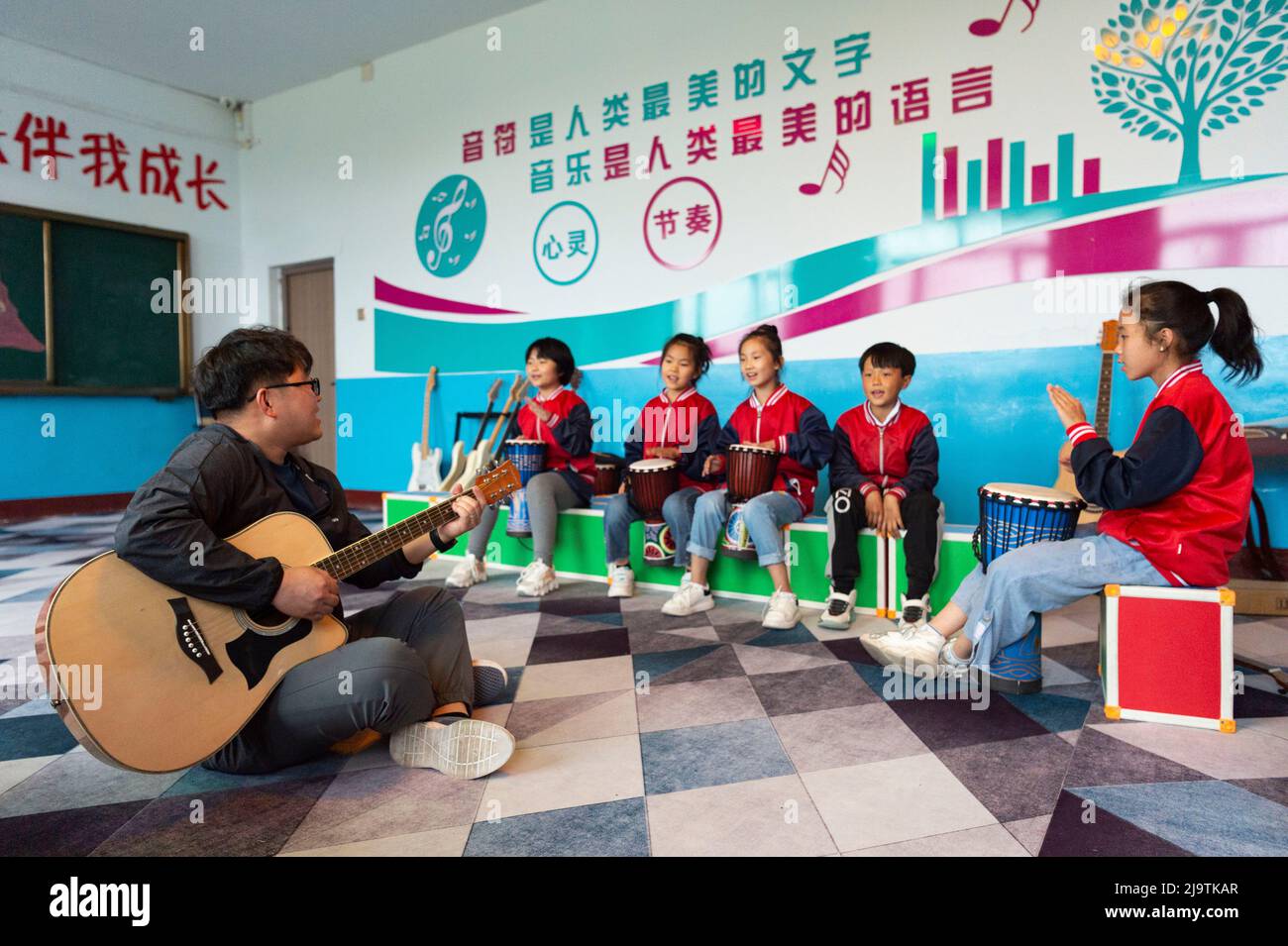 (220525) -- HARBIN, 25. Mai 2022 (Xinhua) -- Lehrer Zhang Yu (1. l) und Kinder in der Musikklasse üben an der zentralen Grundschule der Stadt Renmin in der Stadt Anda, nordöstlich der Provinz Heilongjiang, für Bandaufführungsveranstaltung, 24. Mai 2022. Die Musikklasse der Grundschule wurde im April 2019 gegründet. Die Lehrer der Klasse passen die Texte der populären Lieder an, damit die Kinder singen können, und unterrichten sie ihnen dann während der Mittagspause oder der Clubaktivität. Die Kinder-Chorus-Videos wurden auf kurzen Videoplattform veröffentlicht, die von vielen Netzzenen beliebt und über 1 verdient wurden Stockfoto