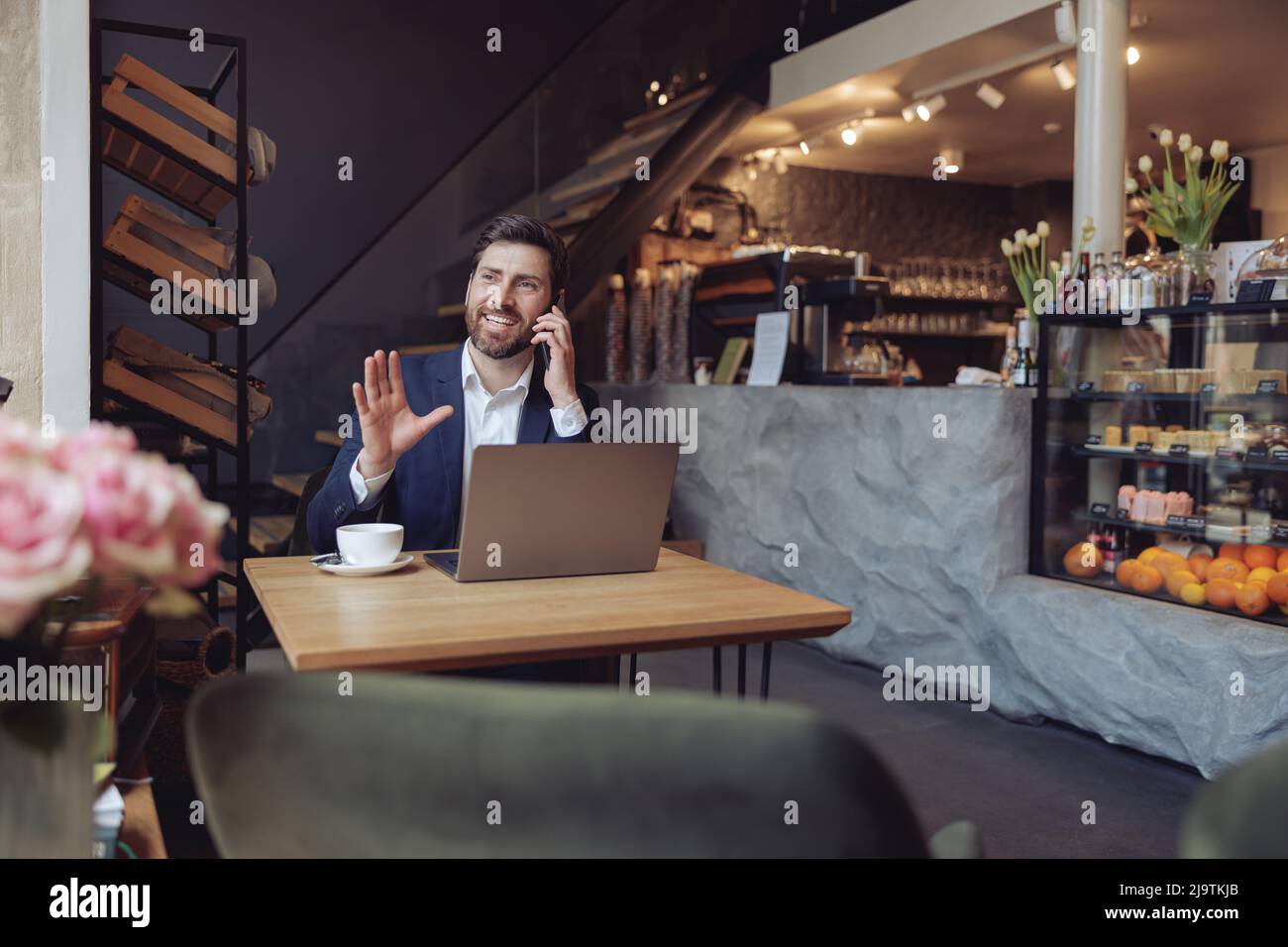 Hübscher, eleganter Mann aus dem Kaukasus, der über das Geschäft am Handy spricht und Kaffee hat. Stockfoto