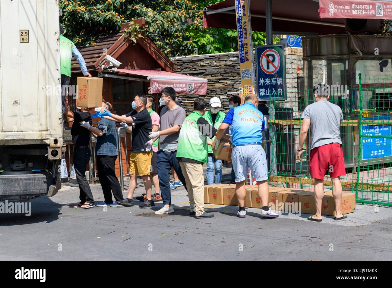 Freiwillige helfen beim Entladen einer Truckvoll von Kisten mit Lebensmitteln, die den Bewohnern während des Lokcdowns in Shanghai gegeben werden. Stockfoto