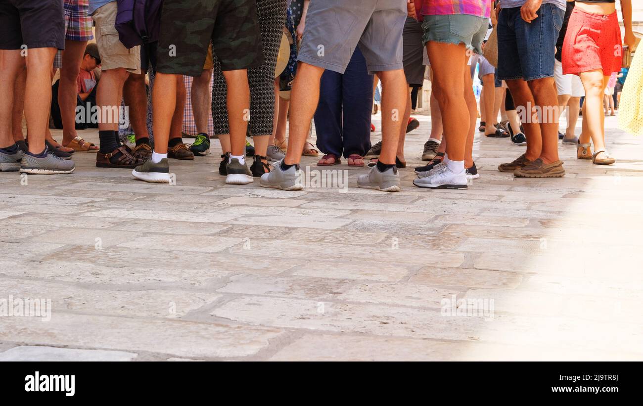 Die Menschen gehen auf dem Fußweg. Gelbe Pflasterplatte. Fussgängerzone bei Tageslicht, Hintergrund. Städtischer Fußweg im sonnigen Sommer. Stockfoto