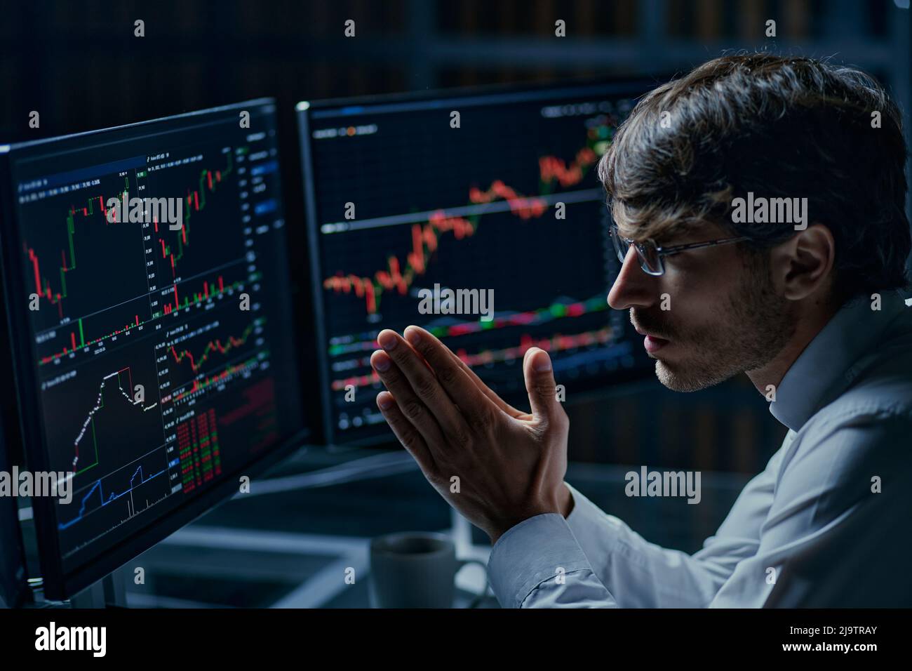Geschäftsmann, der Computermonitore mit Börsendaten betrachtet . Kryptowährung, Finanzen und Technologie. Stockfoto