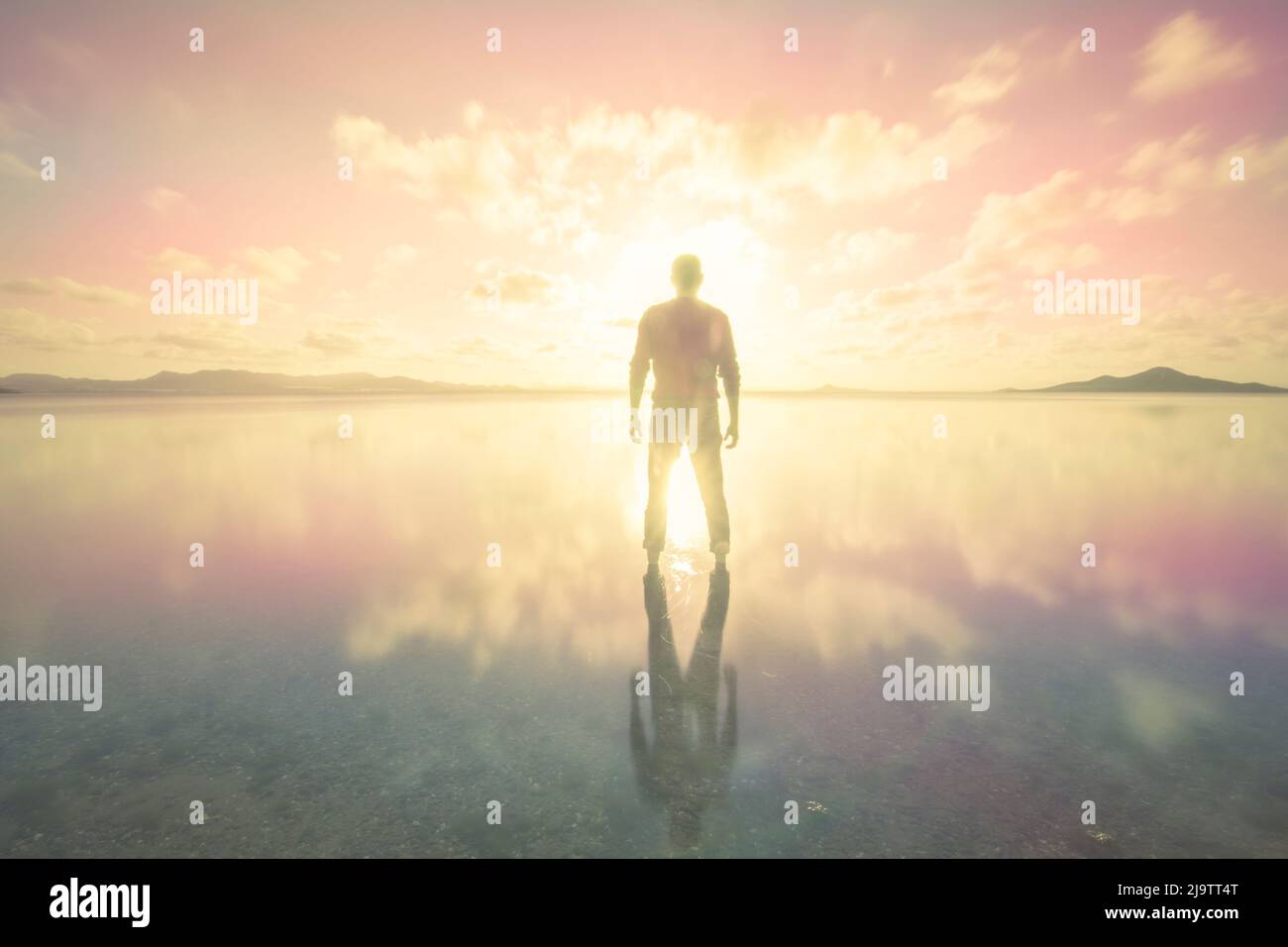 Silhouette eines Mannes über dem farbenprächtigen und rosa Sonnenuntergang des ruhigen Wassers des Mar Menor in der Region Murcia Stockfoto