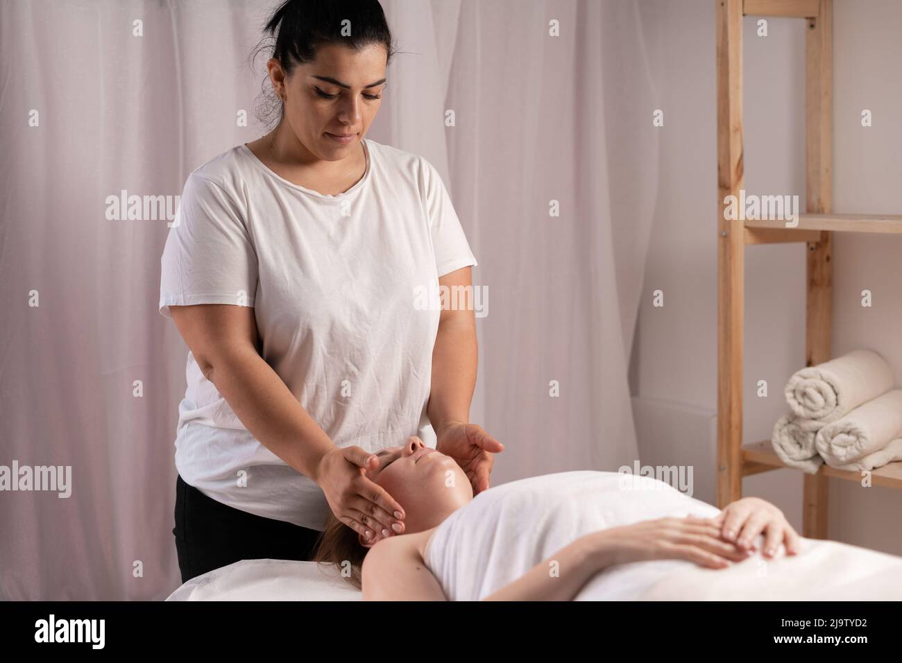 Junge Frau mit Massage im Spa-Salon, manuelle Bildhauerei Gesichtsmassage bukcal. Verjüngende Gesichtsmassage in der Kosmetologie Stockfoto