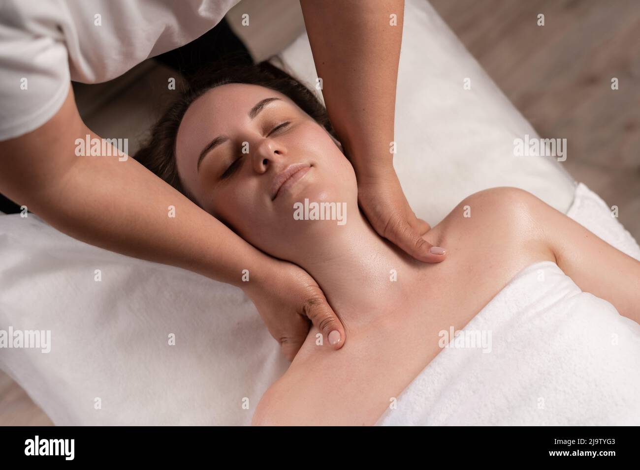 Masseur massiert den Hals einer jungen Frau im Spa-Salon. Nackenmassage im Spa-Salon für ein Mädchen. Konzept der Gesundheitsmassage. Stockfoto