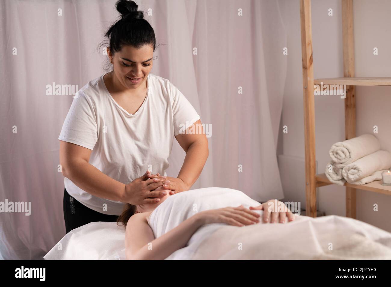 Masseur, der im Spa-Salon eine Massage auf dem Gesicht der Frau macht. Schönheitsbehandlung Stockfoto
