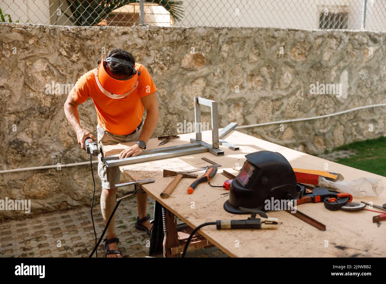 Ein Mann in seinem Hof beschäftigt sich mit Schlosserarbeiten. Hobby, in einer Hauswerkstatt. Stockfoto
