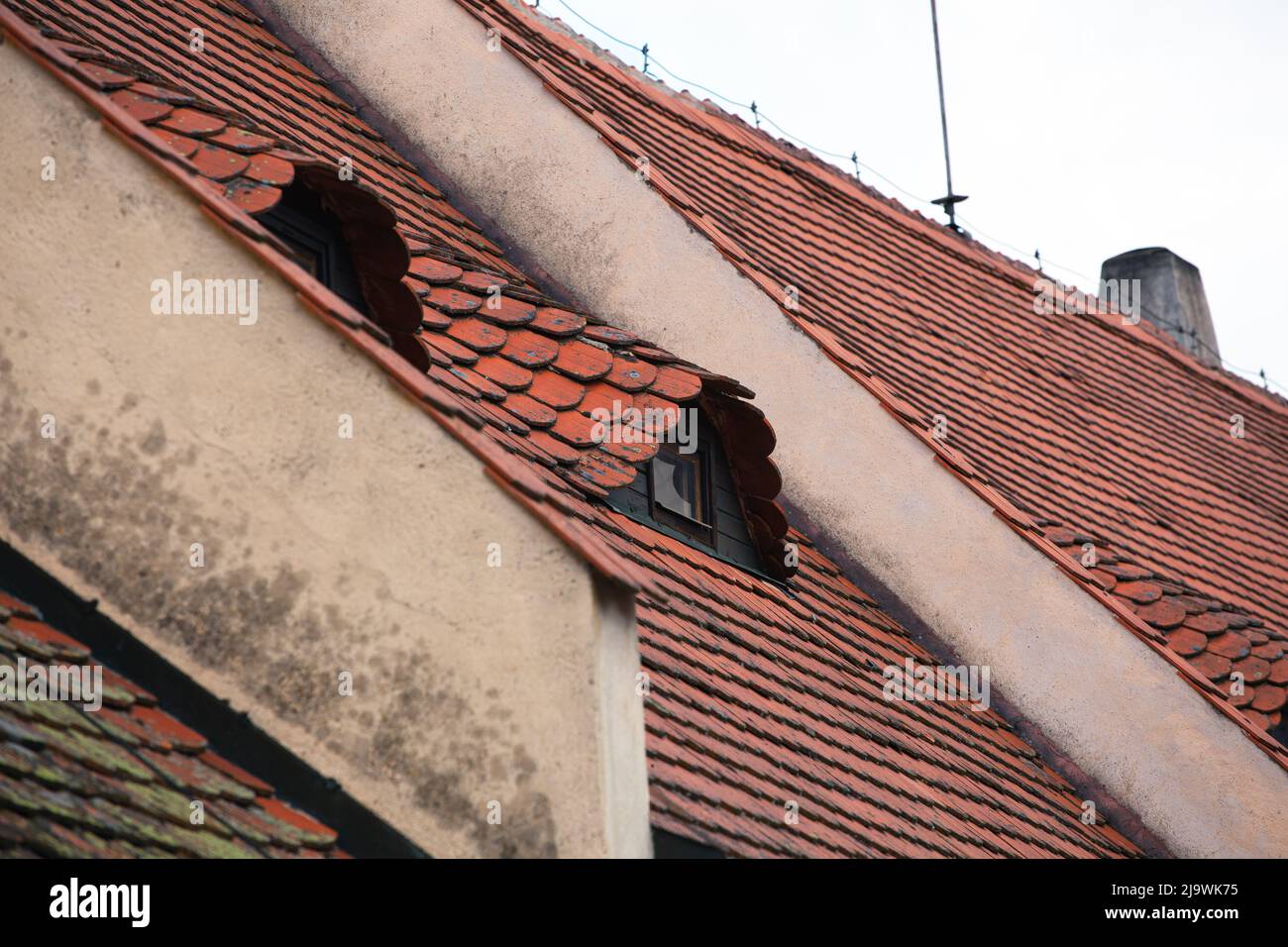 Ein Dach aus flachen Fliesen bedeckt das Gebäude. Auf dem Dach befinden sich zwei kleine halbmondförmige Dachfenster. Stockfoto