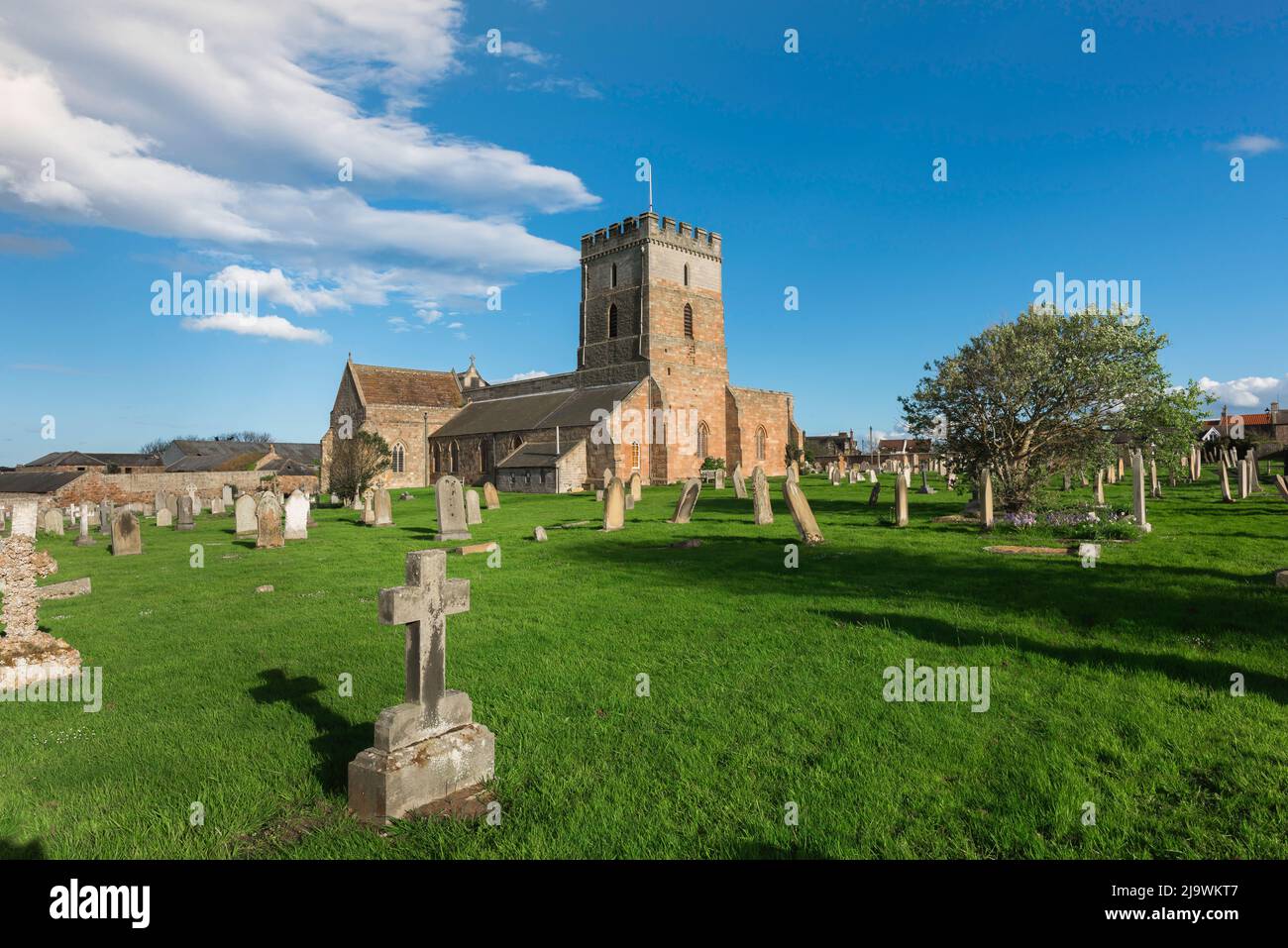 Bamburgh Church, Blick auf die St. Aidan's Church aus dem 12.. Jahrhundert und den malerischen Kirchhof im Küstendorf Northumberland in Bamburgh, England, Großbritannien Stockfoto