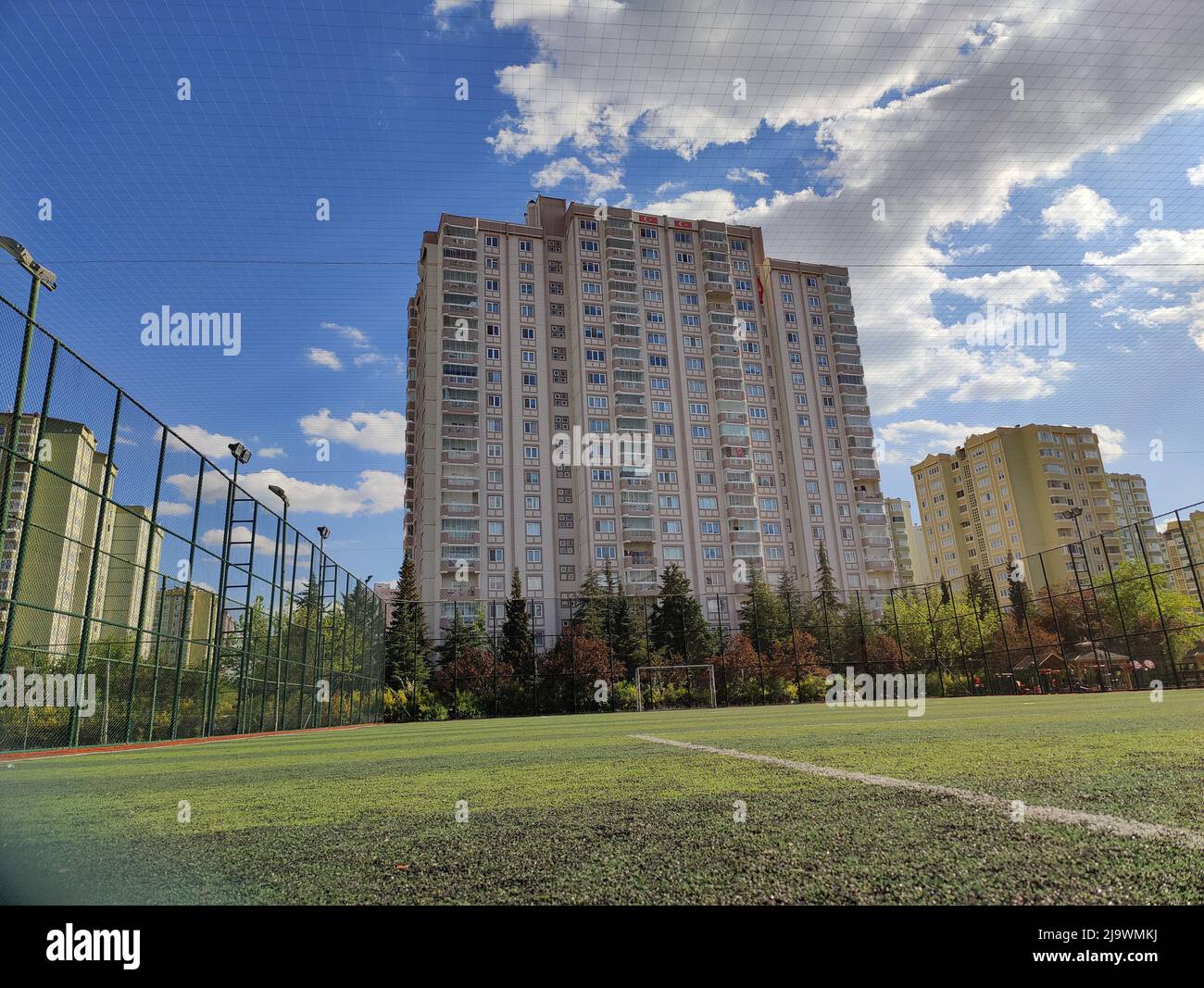 Hohes Gebäude hinter dem Zaun des Fußballfeldes Stockfoto
