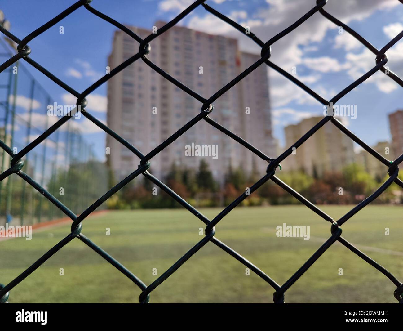 Hohes Gebäude hinter dem Zaun des Fußballfeldes Stockfoto