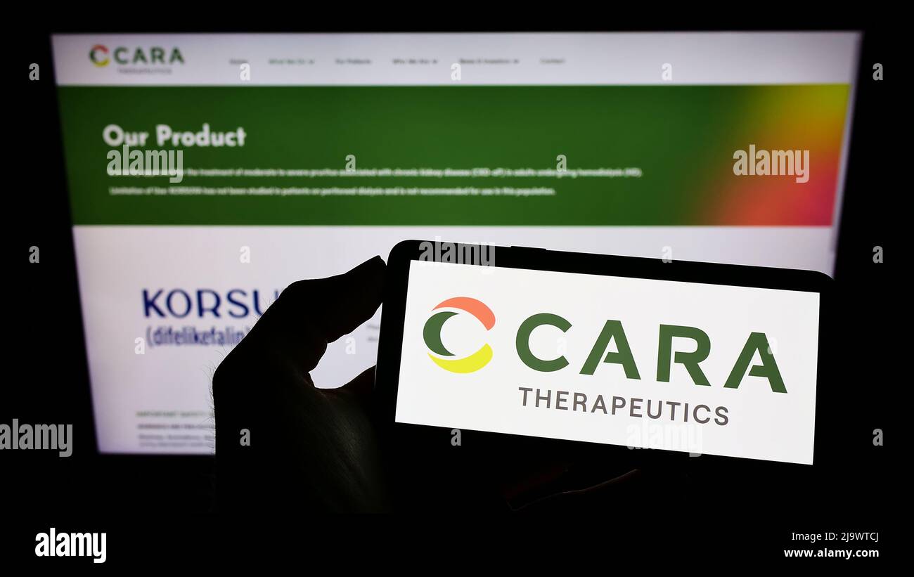 Person mit Mobiltelefon und Logo des amerikanischen Biotech-Unternehmens Cara Therapeutics Inc. Auf dem Bildschirm vor der Webseite. Konzentrieren Sie sich auf die Telefonanzeige. Stockfoto