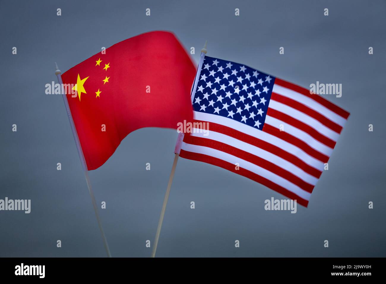 Die Flaggen der Vereinigten Staaten und Chinas vor dem Hintergrund des dunklen, stürmischen Himmels. Konzept des wachsenden politischen Konflikts zwischen Staaten Stockfoto