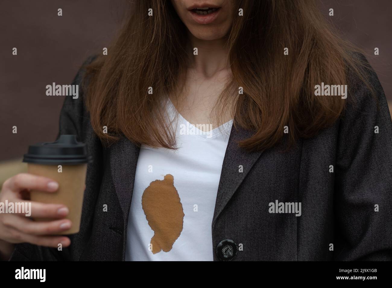 Schmutziger Fleck verschütteten Kaffees beim Gehen, um an Damenbekleidung zu arbeiten. Das Konzept der Reinigung Flecken auf Kleidung Stockfoto