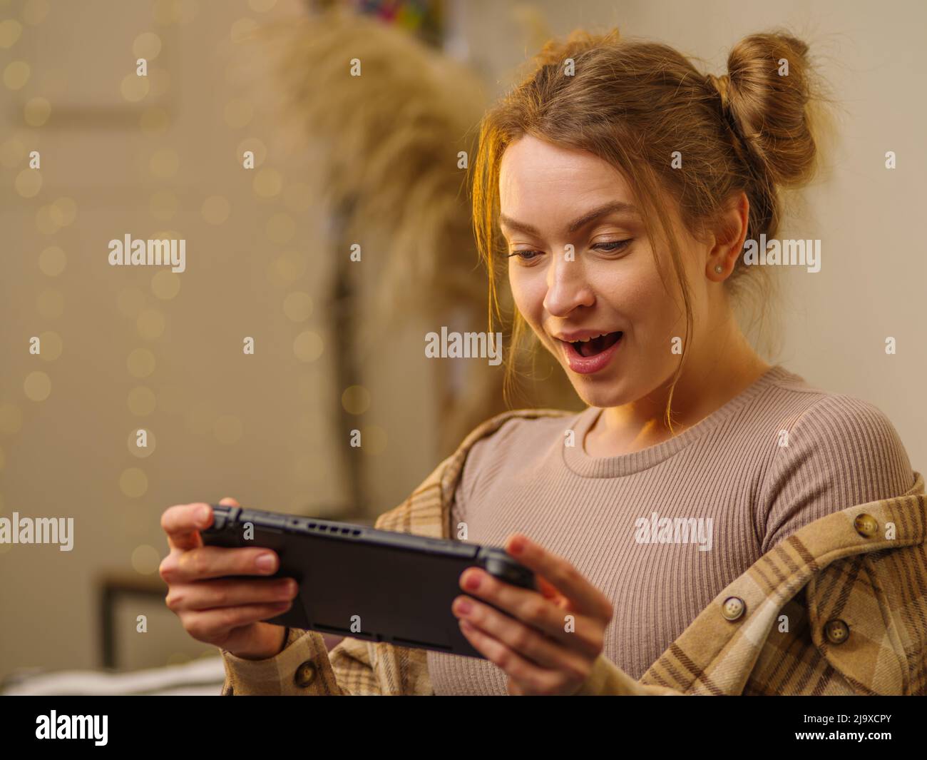 Nahaufnahme. Mädchen Gamer mit einer tragbaren Spielkonsole spielt ein Videospiel online mit Freunden. Reagiert emotional auf den Gewinn. Neue moderne Technologien, out Stockfoto