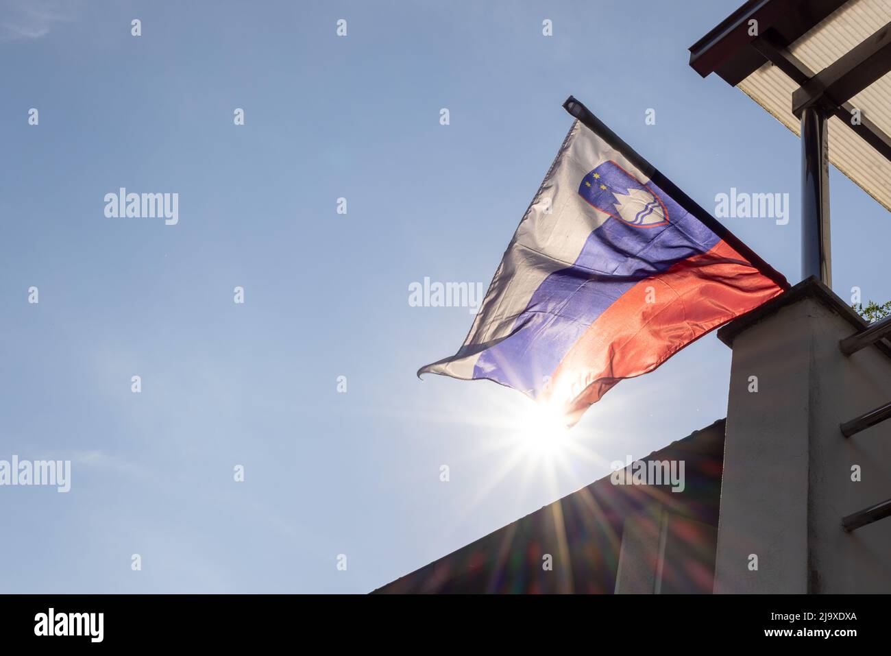 Die slowenische Nationalflagge winkt im Wind und die Sonne scheint Stockfoto