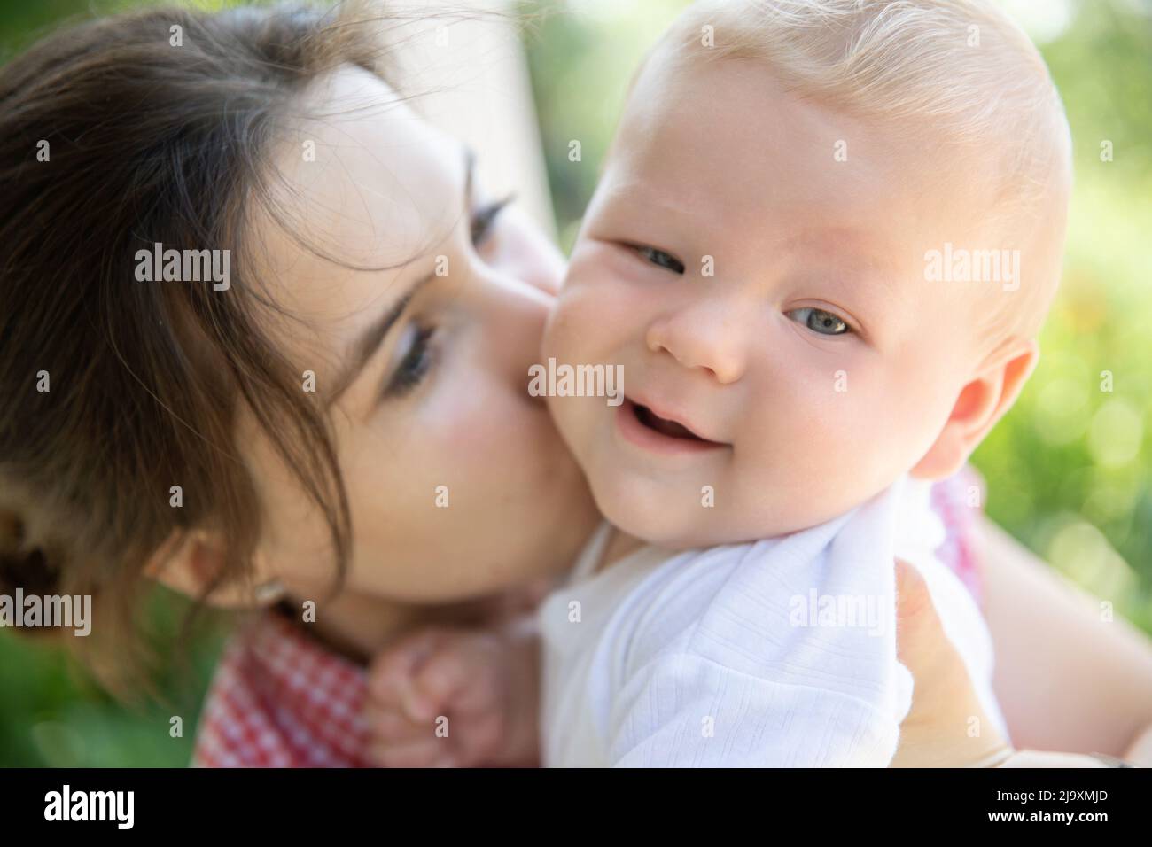 Die junge Mutter umarmt und küsst ihren Sohn Stockfoto