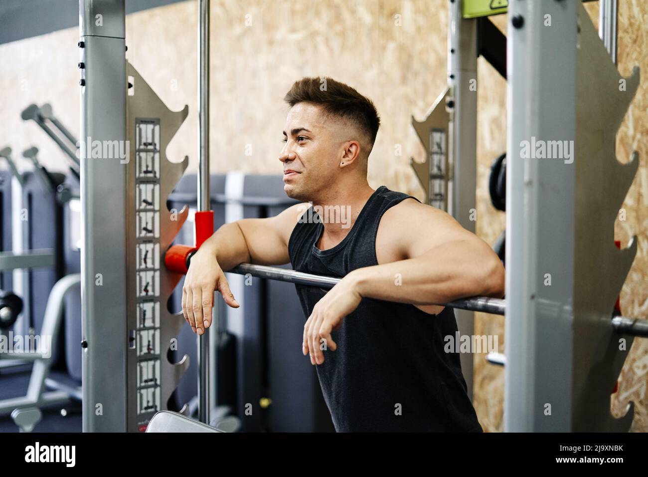 Junger Mann, der sich vom Anheben von Gewichten in einem griffigen Workout Gym erholt Stockfoto