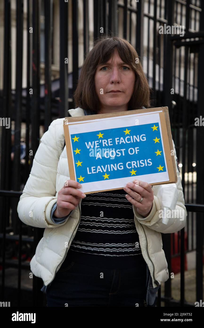 London, Großbritannien. 25 Mai 2022. Eine Protesterin aus dem Stand der Defiance European Movement (SODEM) hält vor der Downing Street ein Schild mit der Aufschrift „Wir stehen vor den Kosten für den Austritt aus der Krise“, das auf die steigenden Lebenshaltungskosten im Land als Folge des Brexit hinweist. Quelle: Kiki Streitberger/Alamy Live News Stockfoto