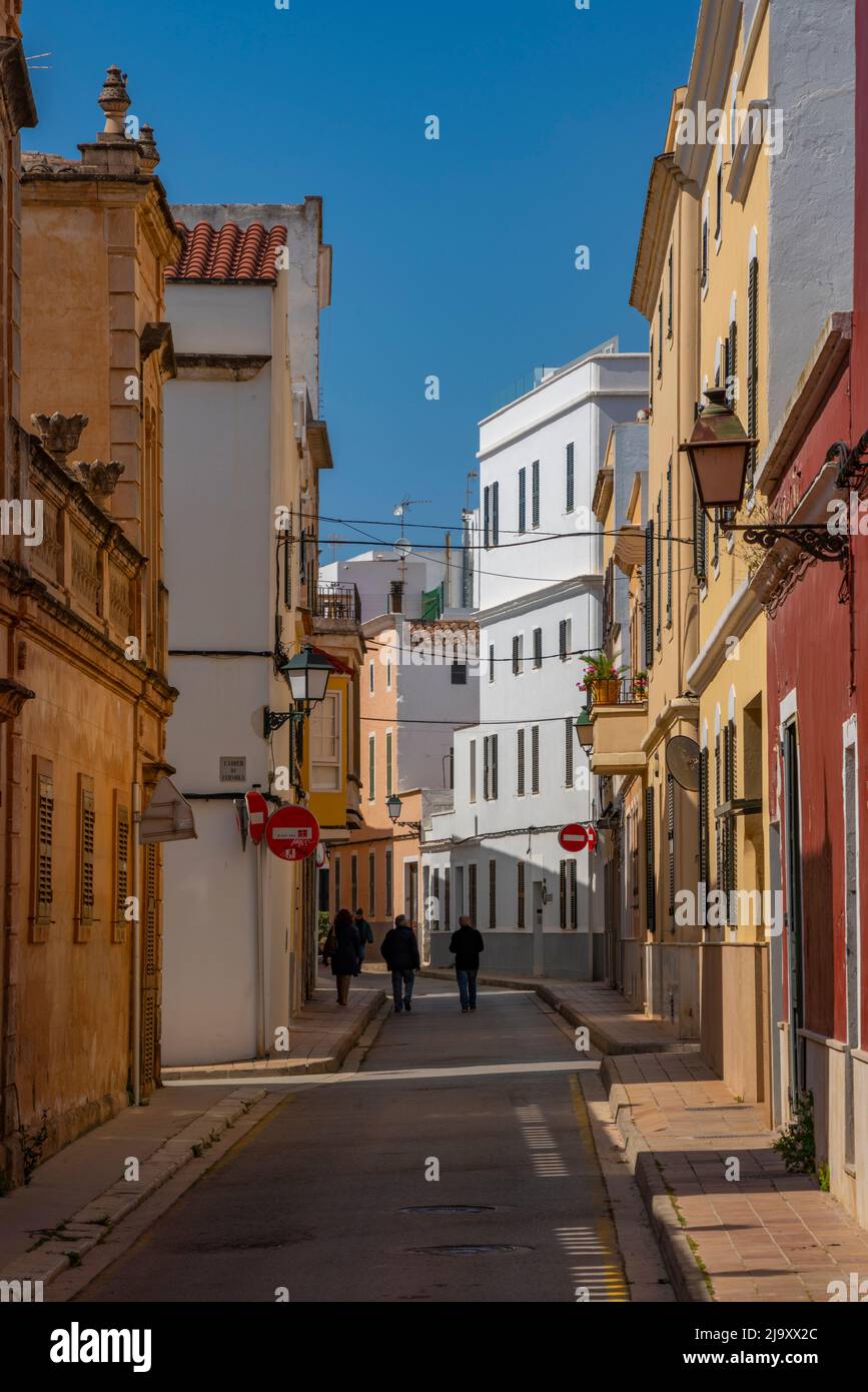 Blick auf ein Paar, das durch eine pastellfarbene Straße in der Altstadt geht, Ciutadella, Menorca, Balearen, Spanien, Europa Stockfoto
