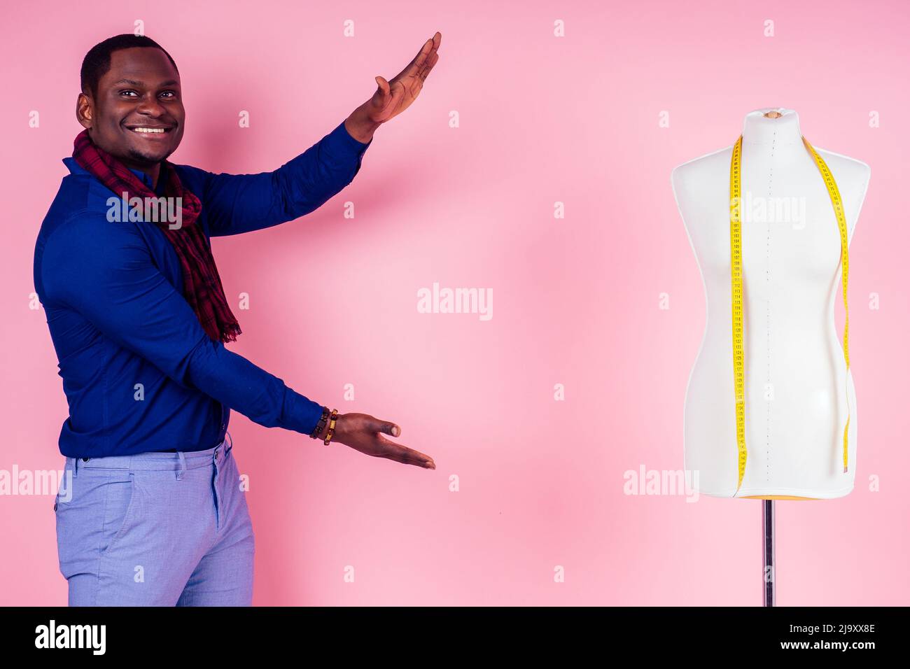 Afroamerikanischer Mann Schneiderei Schneiderei stilvoller männlicher Modelkleiderdesigner, der neben der Schaufensterpuppe auf rosa Hintergrund im Studio posiert Stockfoto