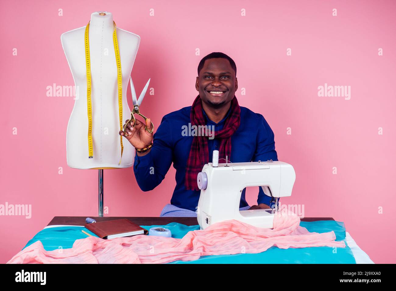 Afroamerikanischer Mann Schneiderei Schneiderei stilvolle männliche Modell Kleidung Designer der Prozess der Schaffung einer neuen Kollektion von Kleidern auf rosa Stockfoto