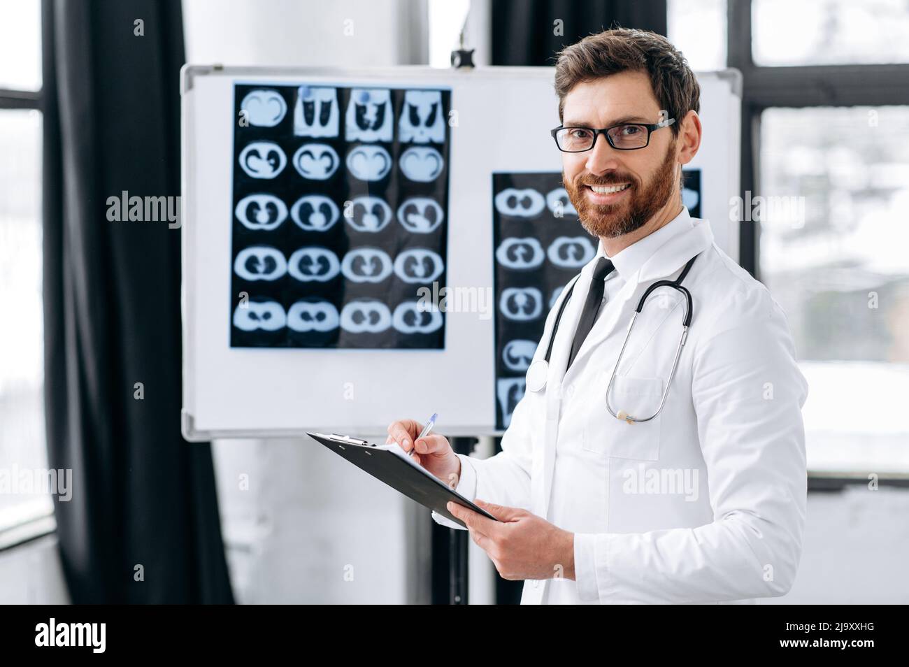 Stolzer, erfahrener kaukasischer Arzt, Chirurg, Pneumologe, in medizinischer Uniform, mit Brille und Stethoskop auf den Schultern, stehen in der Klinik, blicken lächelnd auf die Kamera Stockfoto