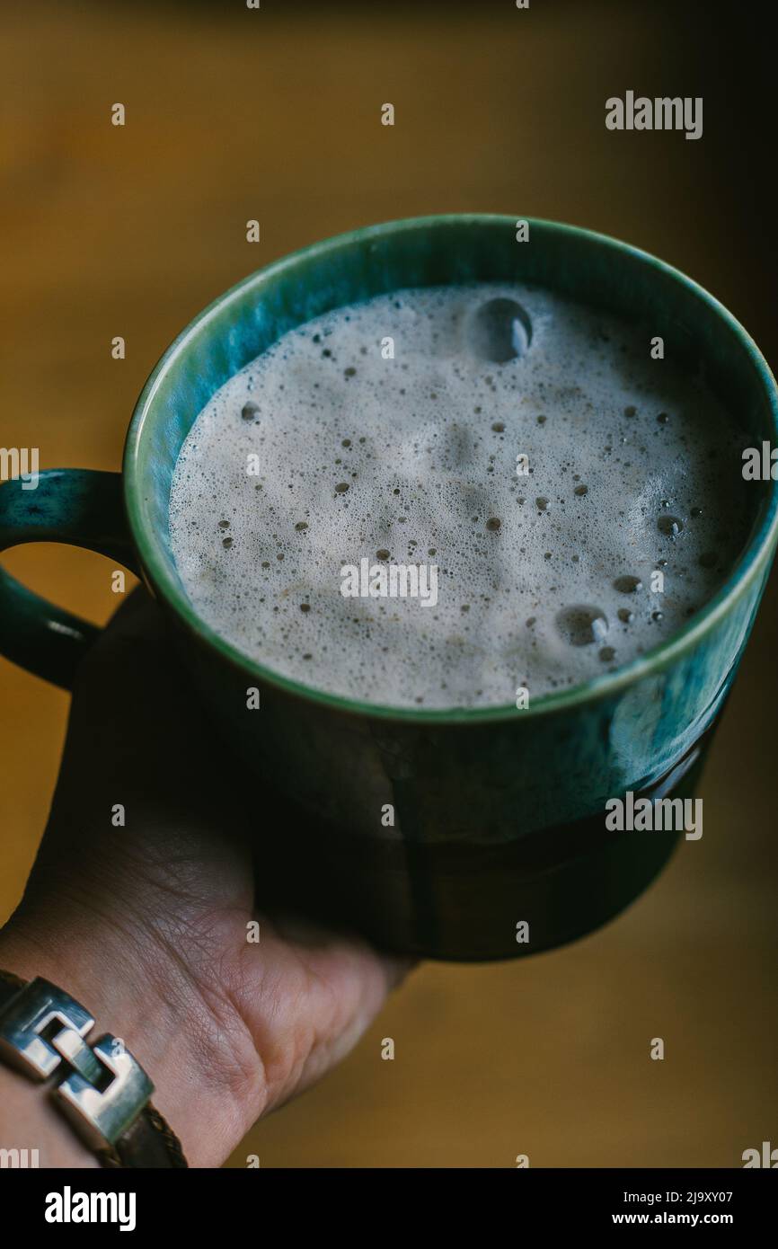 Ein schaumiiger Latte sitzt in der Handfläche Stockfoto