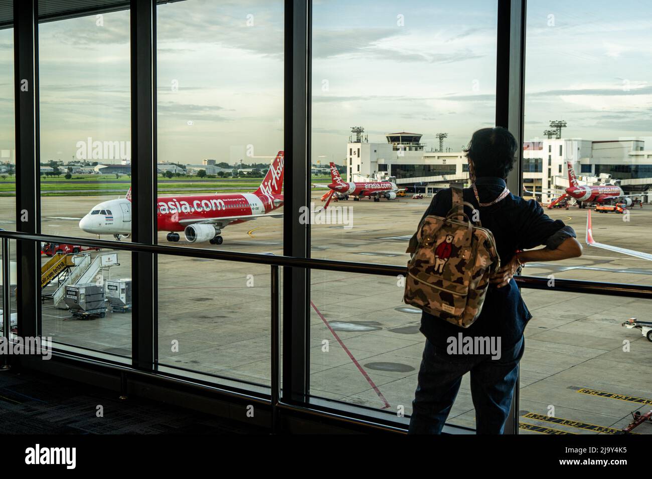 Ein inländischer Reisender beobachtet einen ankommenden Airbus A320-200 von Thai AirAsia (FD) vor einem inländischen Abflugsteig am Don Mueang International Airport (DMK) in Bangkok. Internationale Reisen nach Thailand und inländischer Tourismus im Land werden wieder aufgenommen, da die thailändische Regierung die Einreisebestimmungen im Rahmen ihres Thailand Pass-Programms vereinfacht, so dass internationale Reisende das Land ohne einen schnellen PCR-Test für COVID-19 oder Quarantäne bei der Ankunft betreten können. Die thailändische Regierung hat auch signalisiert, dass die Auflage, Gesichtsmasken im Freien zu tragen, voraussichtlich Mitte Juni 2022 enden wird. Stockfoto