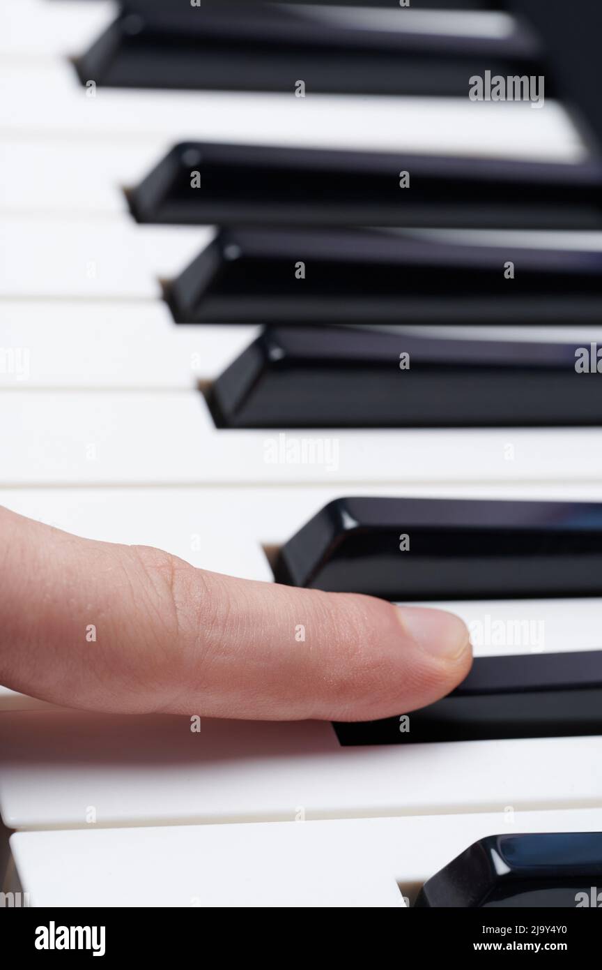 Drücken Sie die schwarze Klaviertaste mit der Nahaufnahme des Fingers Stockfoto