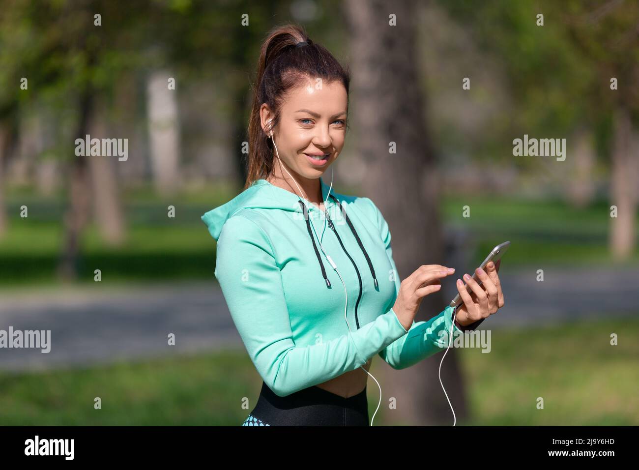 Foto einer jungen Frau, die die Musik auf ihrem Smartphone für eine gute Joggingstimmung aufsetzt. Das Konzept, sich in guter Verfassung zu halten. Stockfoto