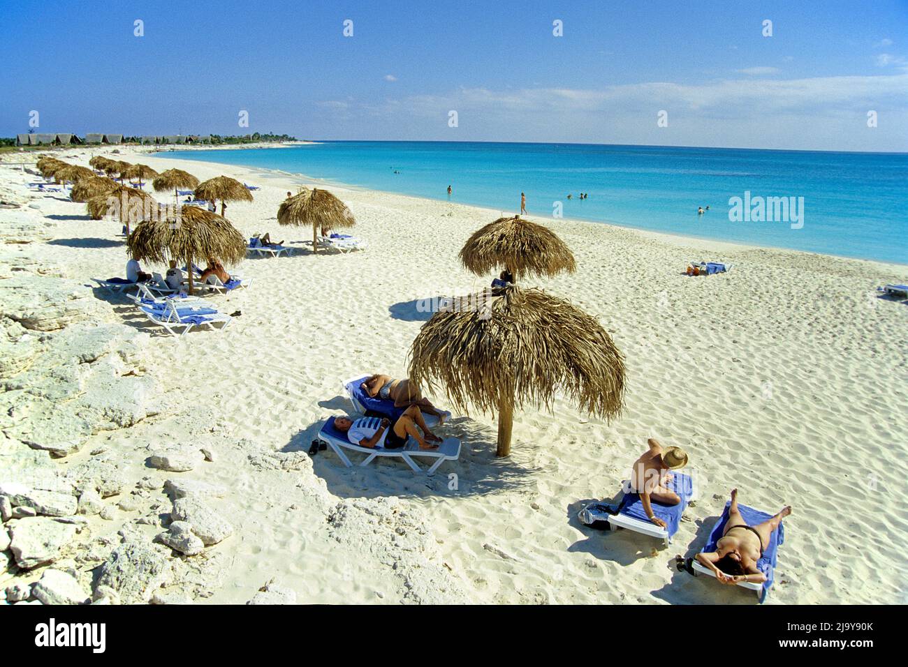 Touristen unter Sonnenschutzschirmen am Strand bei Cayo Largo, Kuba, Karibik | Touristen unter Sonnenschirmen am Strand von Cayo Largo, Kuba, Karibik Stockfoto