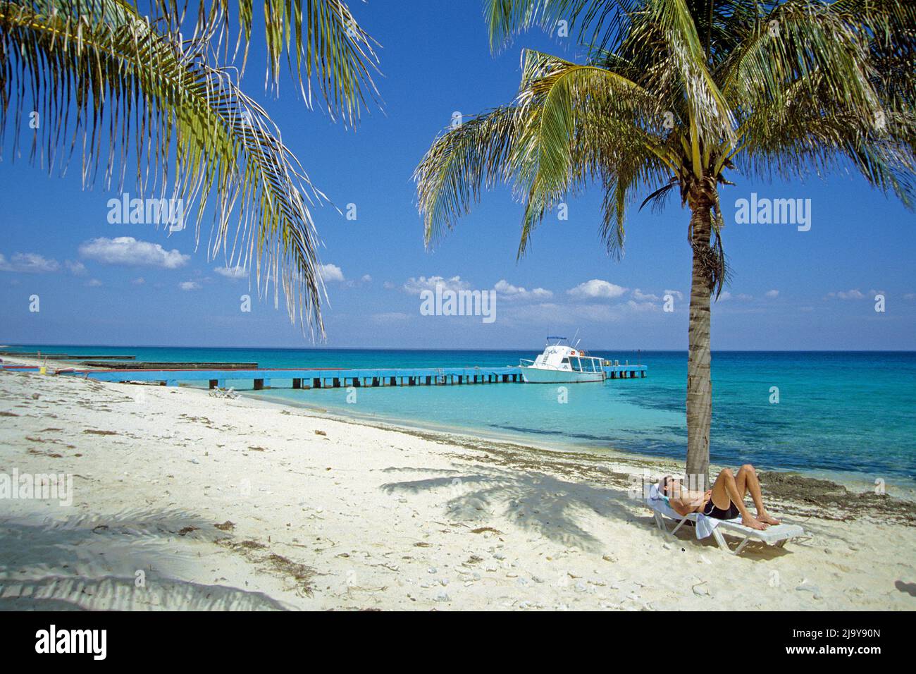Tourist auf einer Sonnenliege unter einer Palme am Strand von Maria la Gorda, Pinar del Rio, Kuba, Karibik | Tourist auf Sonnenbank unter einer Palme am Th Stockfoto