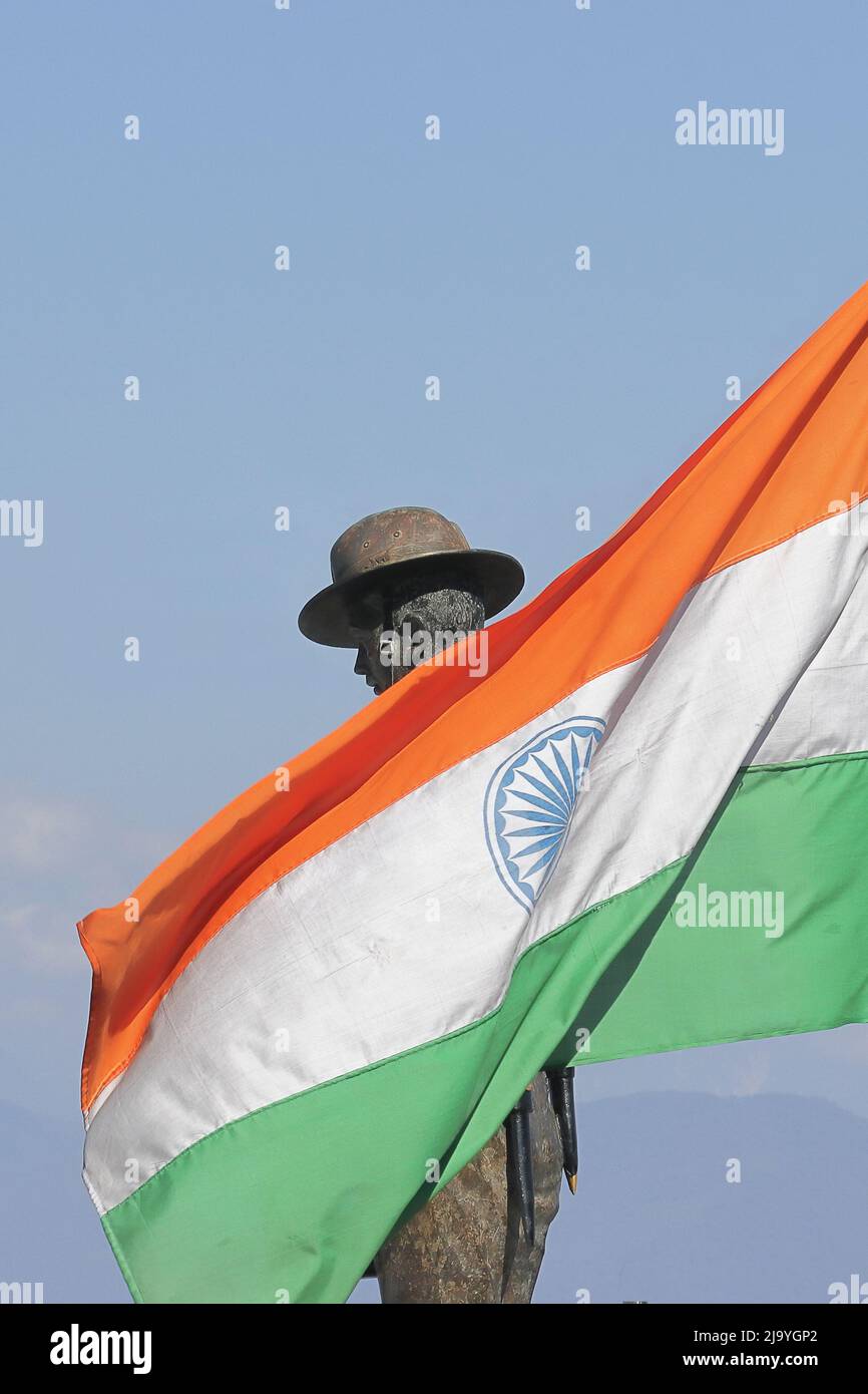 die dreifarbige indische Nationalflagge schwenkt gegen den blauen Himmel mit einer Statue der indischen Armee in der Batasia-Schleife, darjeeling, westbengalen in indien Stockfoto