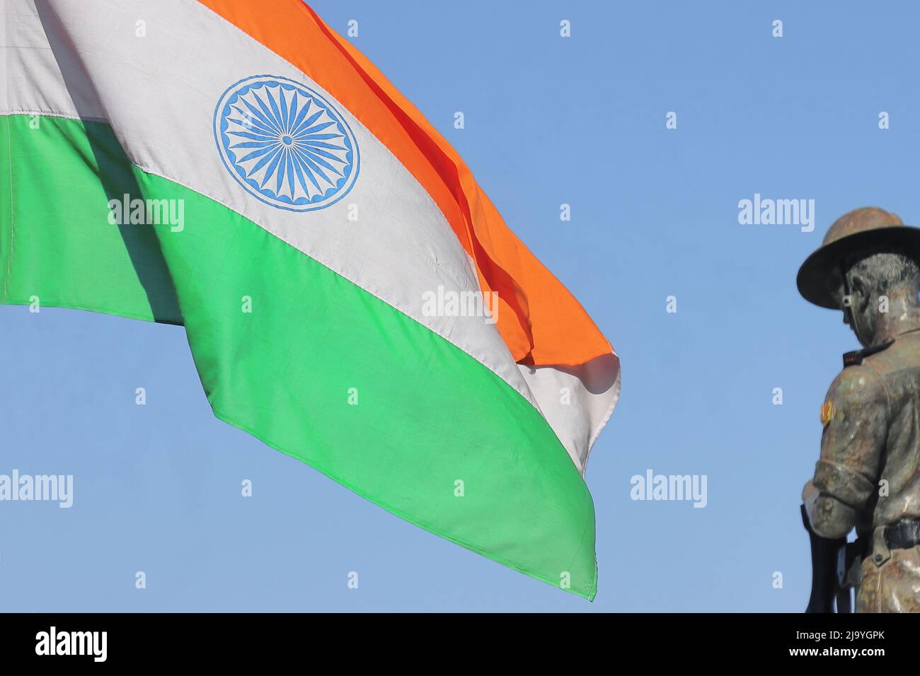 die dreifarbige indische Nationalflagge schwenkt gegen den blauen Himmel mit einer Statue der indischen Armee in der Batasia-Schleife, darjeeling, westbengalen in indien Stockfoto