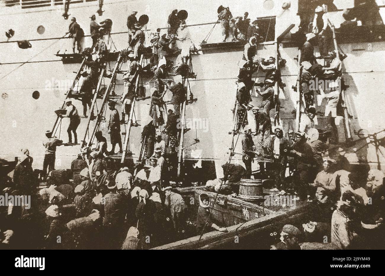 Japan - eine alte Illustration, die Arbeiter zeigt, die als „japanische Kühle“ beschrieben wurden, indem sie Leitern benutzten, um ein großes Schiff mit Kohle von Hand mit Körben in Yokohama zu befeuern, um 1930s ------ 日本 - 1930年代頃、横浜でバスケットを使って石炭を手作業で石炭で燃やすためにはしごを使った「日本のクーリー」と表現された労働者を示す古いイラスト Stockfoto