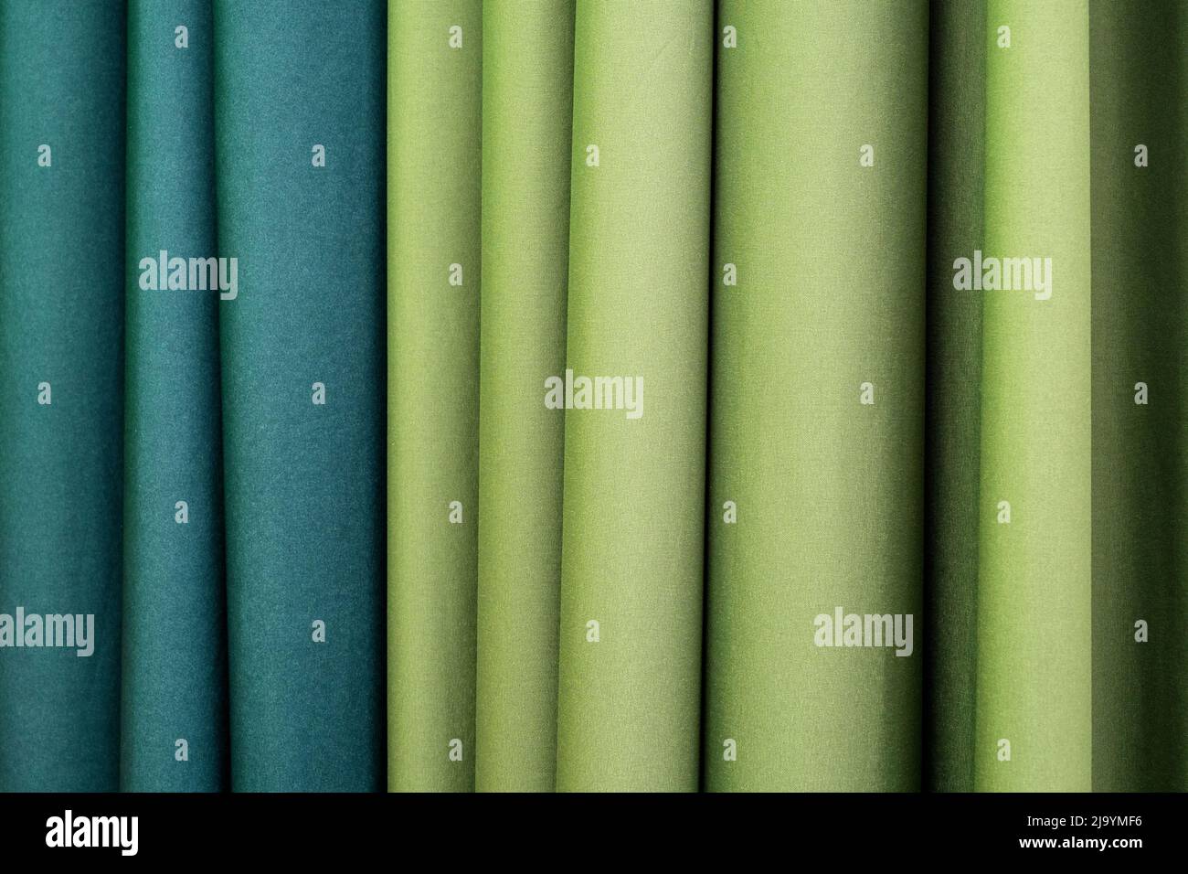 Gefaltete vertikale Vorhänge in Limonen- und blaugrünen Farben als Hotelinterieur Stockfoto