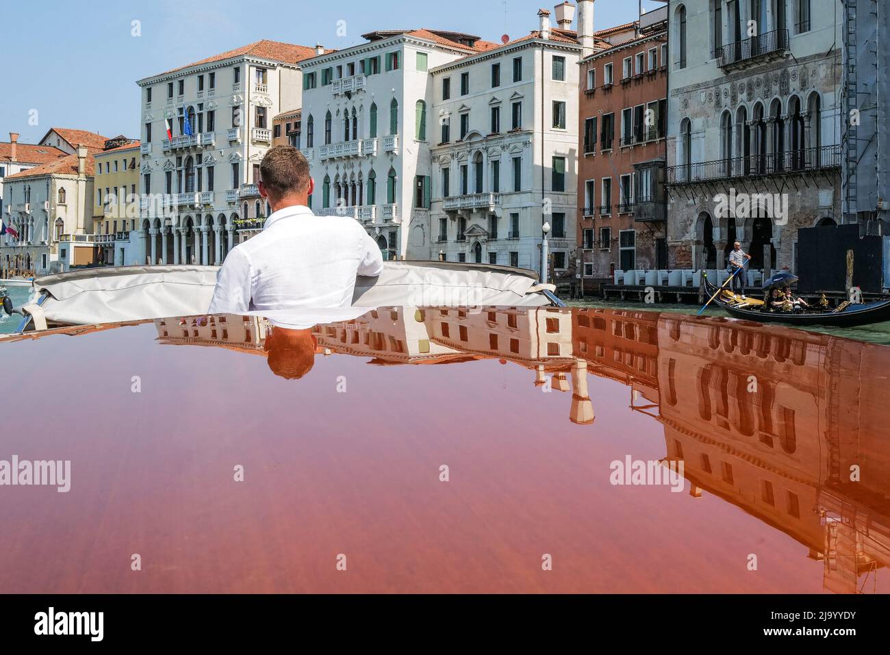 Venezianisches Wassertaxi, das Spiegelungen des Gebäudes am Canale Grande in Venedig zeigt Stockfoto
