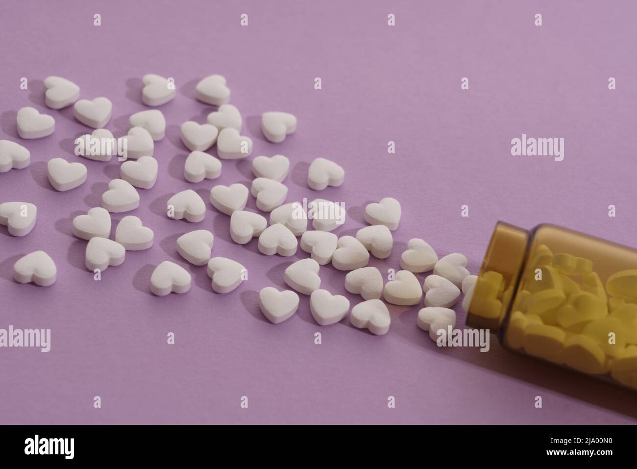 Draufsicht auf verschüttete herzförmige Pillen auf violettem Hintergrund Stockfoto
