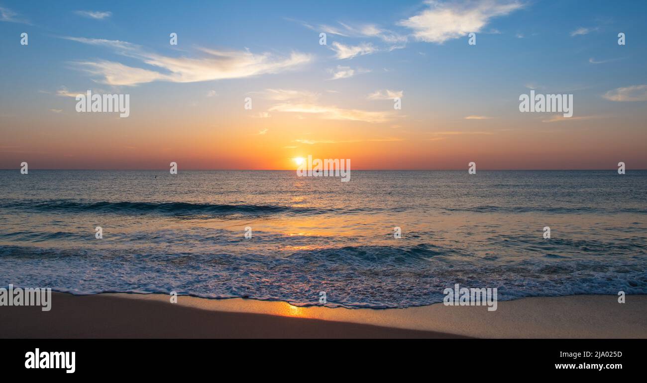 Panoramablick auf den Strand und das Meer mit herrlichem Sonnenaufgang während der goldenen Stunde. Stockfoto