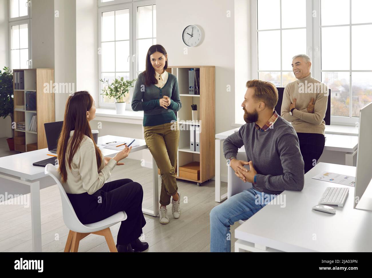 Gruppe von Büromitarbeitern, die während eines informellen Arbeitsgesprächs miteinander kommunizieren oder miteinander sprechen. Stockfoto